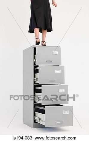 Woman using filing cabinet as steps View Large Photo Image Stock Image - Woman using filing cabinet as steps. Fotosearch