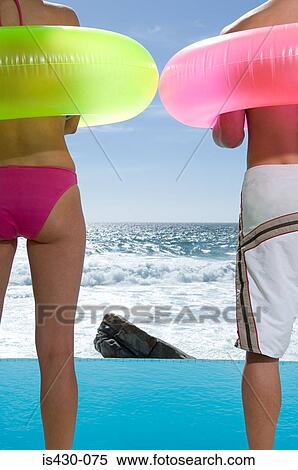 Couple standing by infinity pool View Large Photo Image Stock Photography - Couple standing by infinity pool. Fotosearch