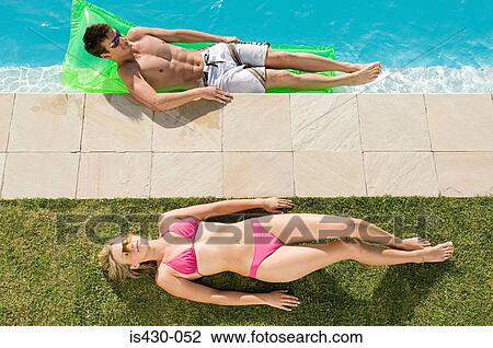 Couple sunbathing at the pool View Large Photo Image Stock Image - Couple sunbathing at the pool. Fotosearch
