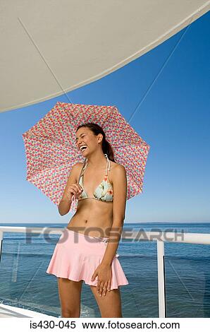 Stock Photography - Happy woman on balcony with umbrella. Fotosearch
