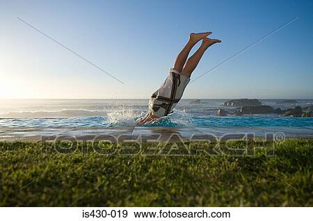 Stock Photo - Man diving into infinity pool. Fotosearch