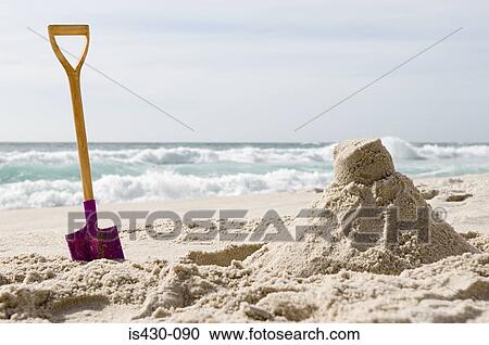 Stock Image - Spade and sandcastle. Fotosearch