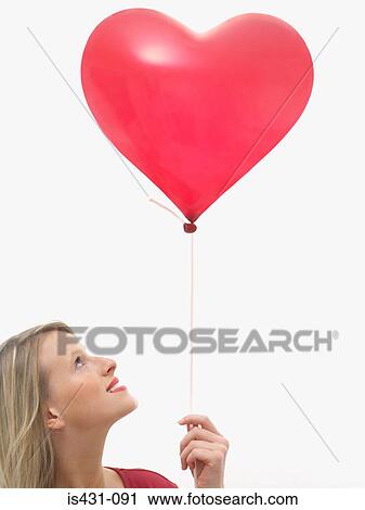 Stock Image - Woman holding heart shaped balloon. Fotosearch