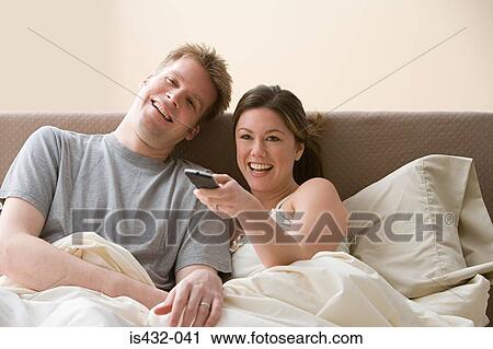 Stock Image - Couple watching television in bed. Fotosearch