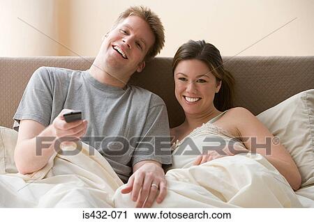 Couple watching television in bed View Large Photo Image Stock Image - Couple watching television in bed. Fotosearch