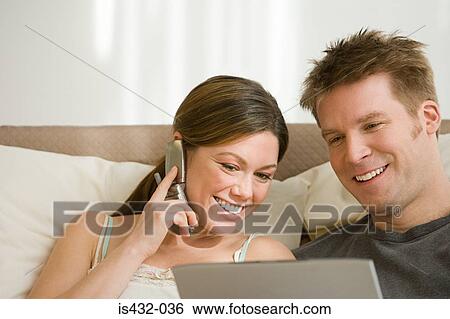 Stock Photograph - Couple with cellphone and laptop. Fotosearch