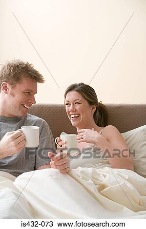 Stock Image - Happy couple having coffee in bed. Fotosearch