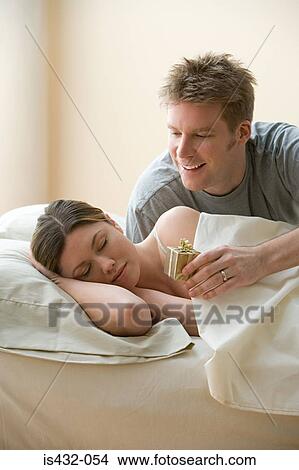 Husband with gift for sleeping wife View Large Photo Image Picture - Husband with gift for sleeping wife. Fotosearch