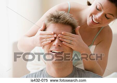 Stock Photography - Woman covering husband's eyes. Fotosearch