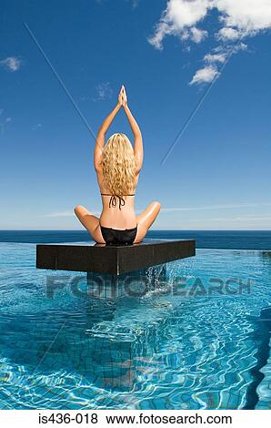 Stock Photo - Woman practicing yoga on a platform. Fotosearch