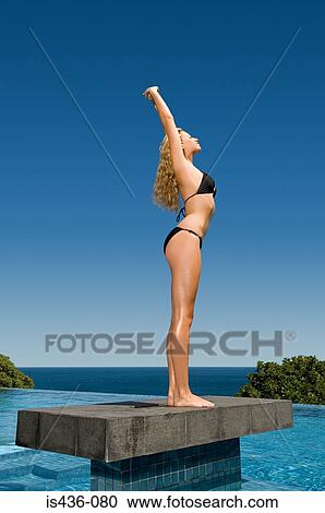 Stock Image - Woman standing on platform in pool. Fotosearch