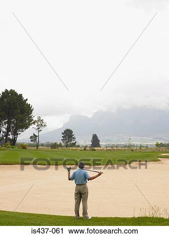 Stock Image - Golfer looking over sand trap. Fotosearch