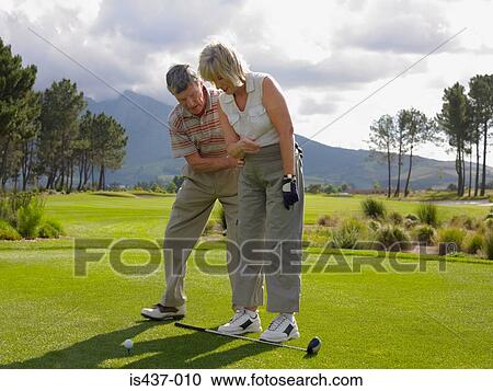 Stock Image - Man giving woman a golf lesson. Fotosearch