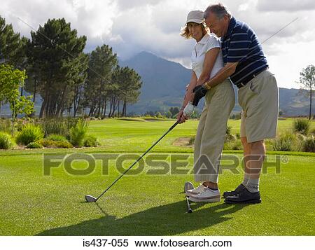 Stock Photography - Man giving woman a golf lesson. Fotosearch