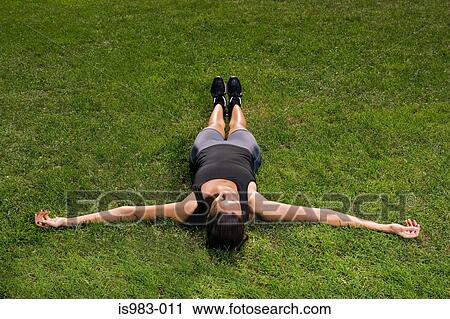 Stock Image - Female athlete lying on the grass. Fotosearch
