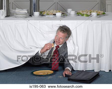Businessman eating in secret View Large Photo Image Stock Image - Businessman eating in secret. Fotosearch