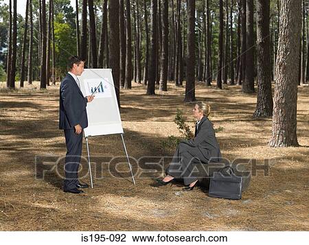 Stock Image - Office workers holding a meeting in forest. Fotosearch