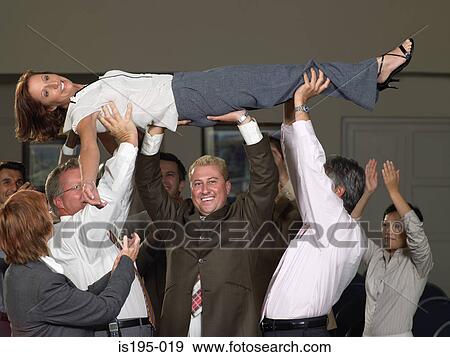 Stock Photo - Office workers lifting colleague up. Fotosearch