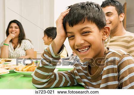 Stock Image - Smiling boy at dining table. Fotosearch