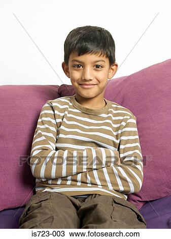 Smiling boy sitting on a sofa View Large Photo Image Stock Image - Smiling boy sitting on a sofa. Fotosearch