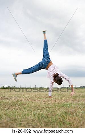 Girl doing a cartwheel in a field View Large Photo Image Stock Image - Girl doing a cartwheel in a field. Fotosearch