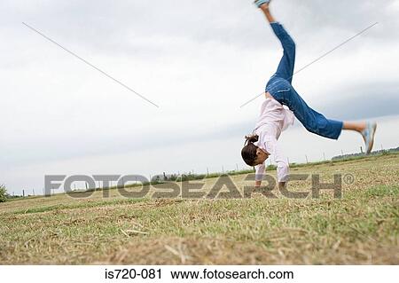 Girl doing a cartwheel in a field View Large Photo Image Stock Image - Girl doing a cartwheel in a field. Fotosearch