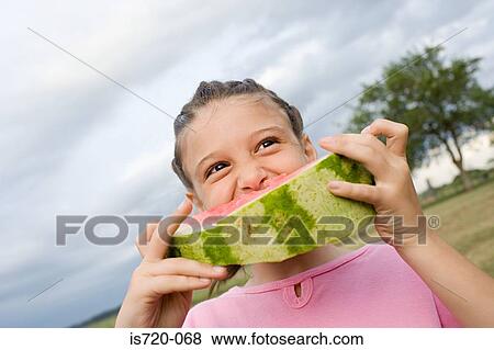 Girl eating a large slice of watermelon View Large Photo Image Stock Photo - Girl eating a large slice of watermelon. Fotosearch