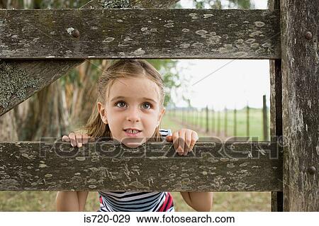 Girl looking through a fence View Large Photo Image Stock Photo - Girl looking through a fence. Fotosearch