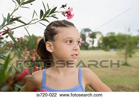 Stock Image - Girl standing next to a blossoming tree. Fotosearch