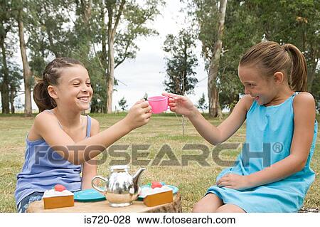Stock Photo - Girls having a tea party in field. Fotosearch
