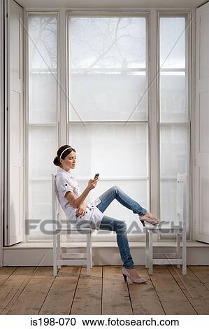 Woman on chairs with handheld computer View Large Photo Image Stock Image - Woman on chairs with handheld computer. Fotosearch