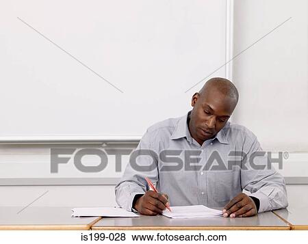 Teacher marking paperwork View Large Photo Image Stock Photo - Teacher marking paperwork. Fotosearch
