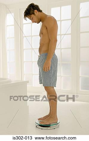 Stock Image - Man weighing himself. Fotosearch