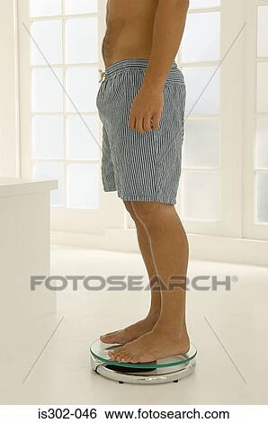 Man weighing himself View Large Photo Image Stock Photograph - Man weighing himself. Fotosearch