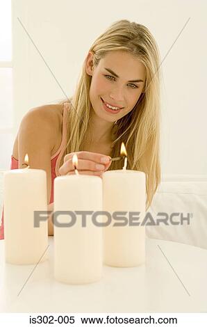 Stock Photography - Woman lighting three candles. Fotosearch