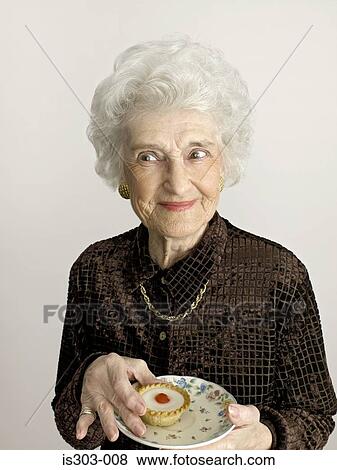 Stock Photo - Senior woman with cherry bakewell tart. Fotosearch