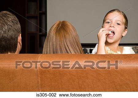 Girl eating popcorn with family View Large Photo Image Stock Image - Girl eating popcorn with family. Fotosearch