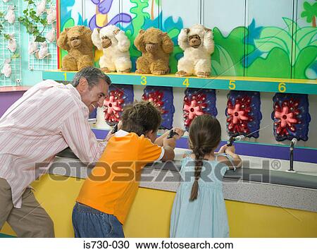 Stock Image - Father and kids on fairground stall. Fotosearch