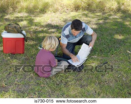 Stock Photography - Father and son reading instructions for tent. Fotosearch
