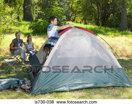 Stock Photo - Father putting up tent. Fotosearch