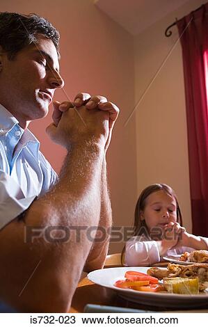 Stock Image - Father and daughter saying grace. Fotosearch