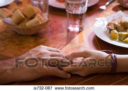 Holding hands at the dinner table View Large Photo Image Stock Photo - Holding hands at the dinner table. Fotosearch
