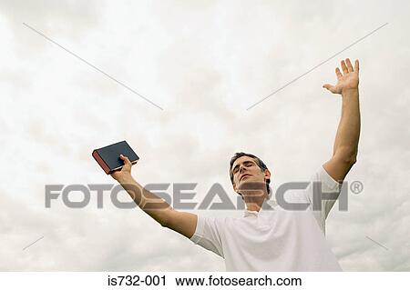 Man holding the bible with arms raised View Large Photo Image Stock Image - Man holding the bible with arms raised. Fotosearch
