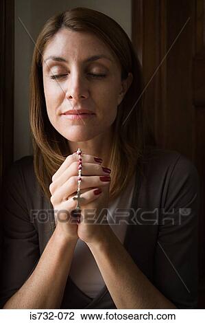 Stock Image - Woman praying with rosary. Fotosearch