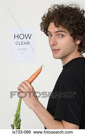 Stock Photograph - Young man holding carrot. Fotosearch