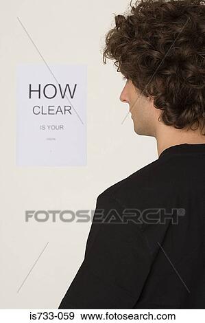 Young man looking at sight test chart View Large Photo Image Stock Photo - Young man looking at sight test chart. Fotosearch