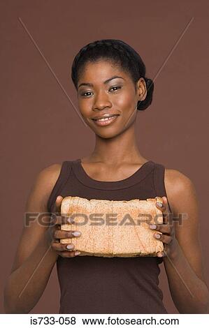 Young woman holding a loaf of bread View Large Photo Image Stock Photo - Young woman holding a loaf of bread. Fotosearch