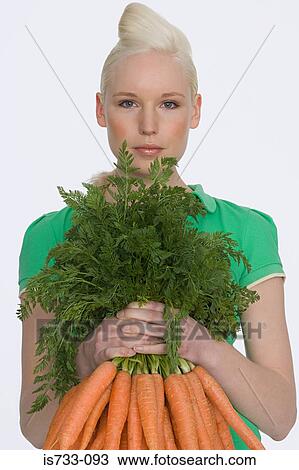 Young woman holding carrots View Large Photo Image Stock Image - Young woman holding carrots. Fotosearch