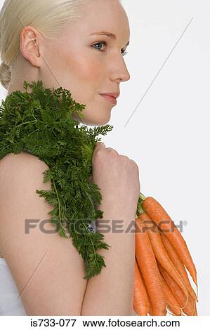 Young woman holding carrots View Large Photo Image Stock Photo - Young woman holding carrots. Fotosearch