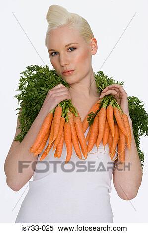 Stock Photography - Young woman holding carrots. Fotosearch